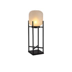 Slightly angled view of a taller Clérachic lantern, lit on a white background, with a black cross-braced frame.