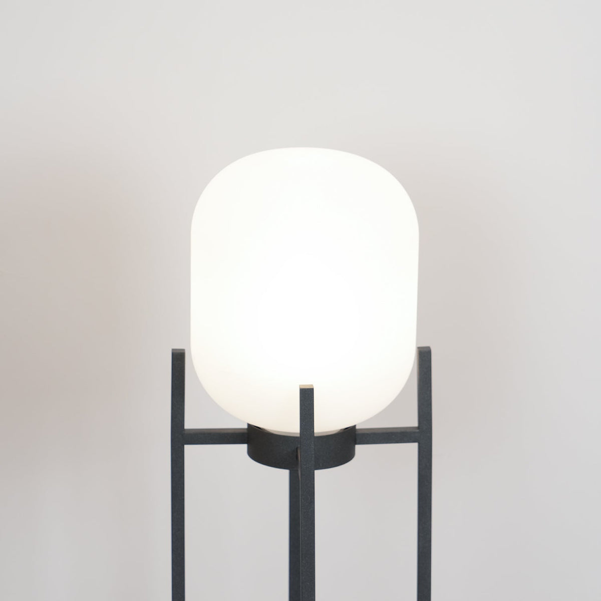 Close view of the rounded white glass shade of this Clérachic lantern, held in the top of its charcoal frame.