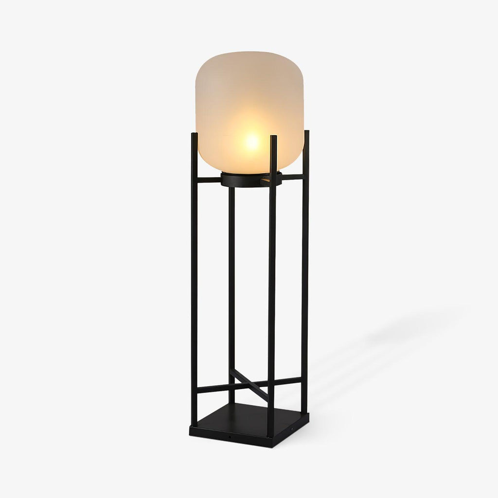 Angled view of this Clérachic lantern lit on a pale background, with a frosted shade on a black frame and a soft shadow.