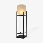 Angled view of this Clérachic lantern lit on a pale background, with a frosted shade on a black frame and a soft shadow.