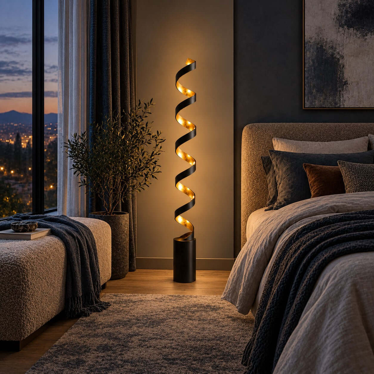 Close to a bed with a chunky grey knit throw, this Clérachic black and gold spiral floor lamp glows against a dark wall and a tall plant.