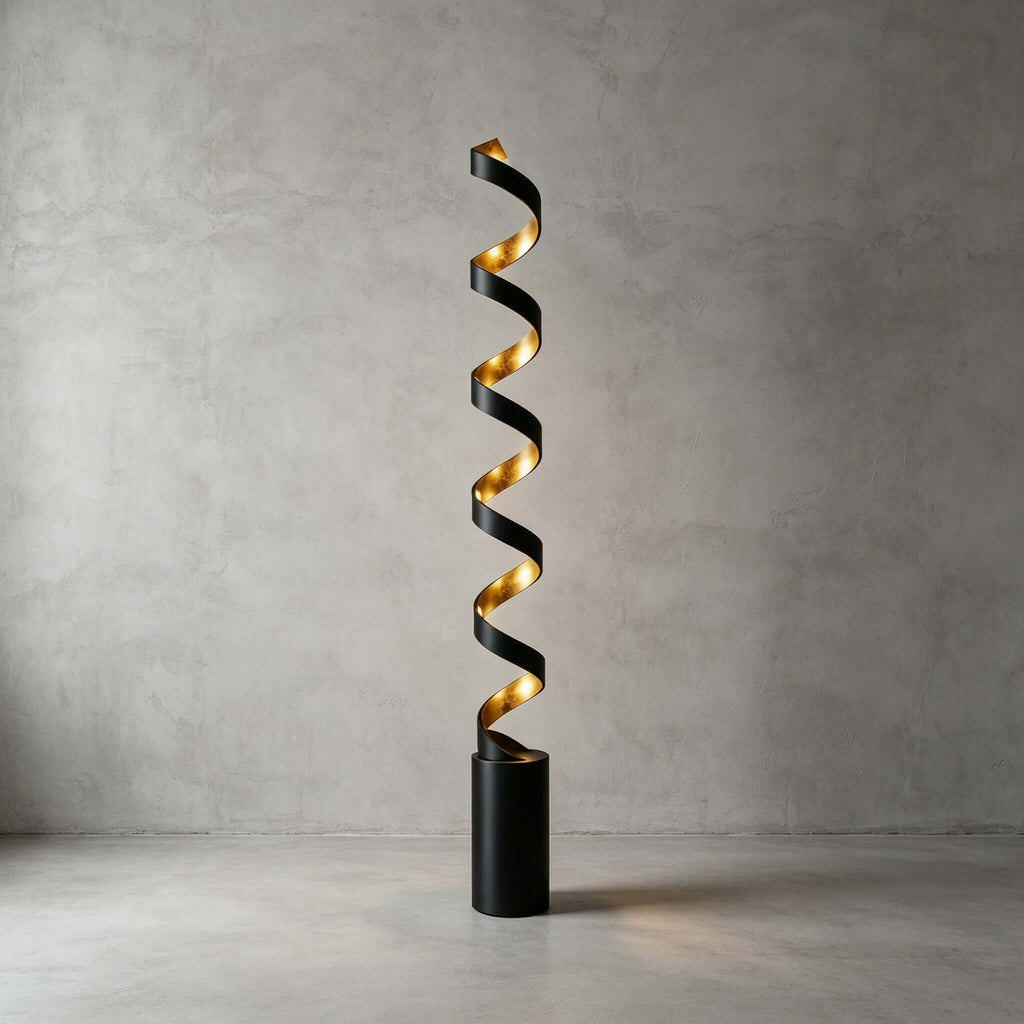 This Clérachic spiral floor lamp lit in front of a bare concrete wall, its black cylinder base standing on a smooth pale floor.