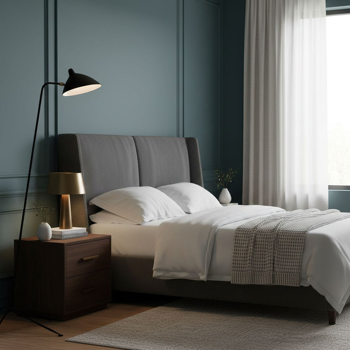 In a bedroom with blue-grey panelled walls, this Clérachic floor lamp reaches over a grey upholstered bed.