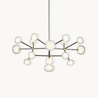 Black-framed Clérachic chandelier on a white backdrop, with brass joints and clear-rimmed glass globes branching from a central stem on a black rod.