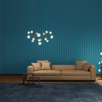 Lit Clérachic chandelier on a teal slatted wall above a tan sofa, with a blue rug and two small tables.