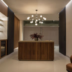 A Clérachic chandelier lit in a dim, warm room above a walnut-fronted island with a vase of burgundy stems.
