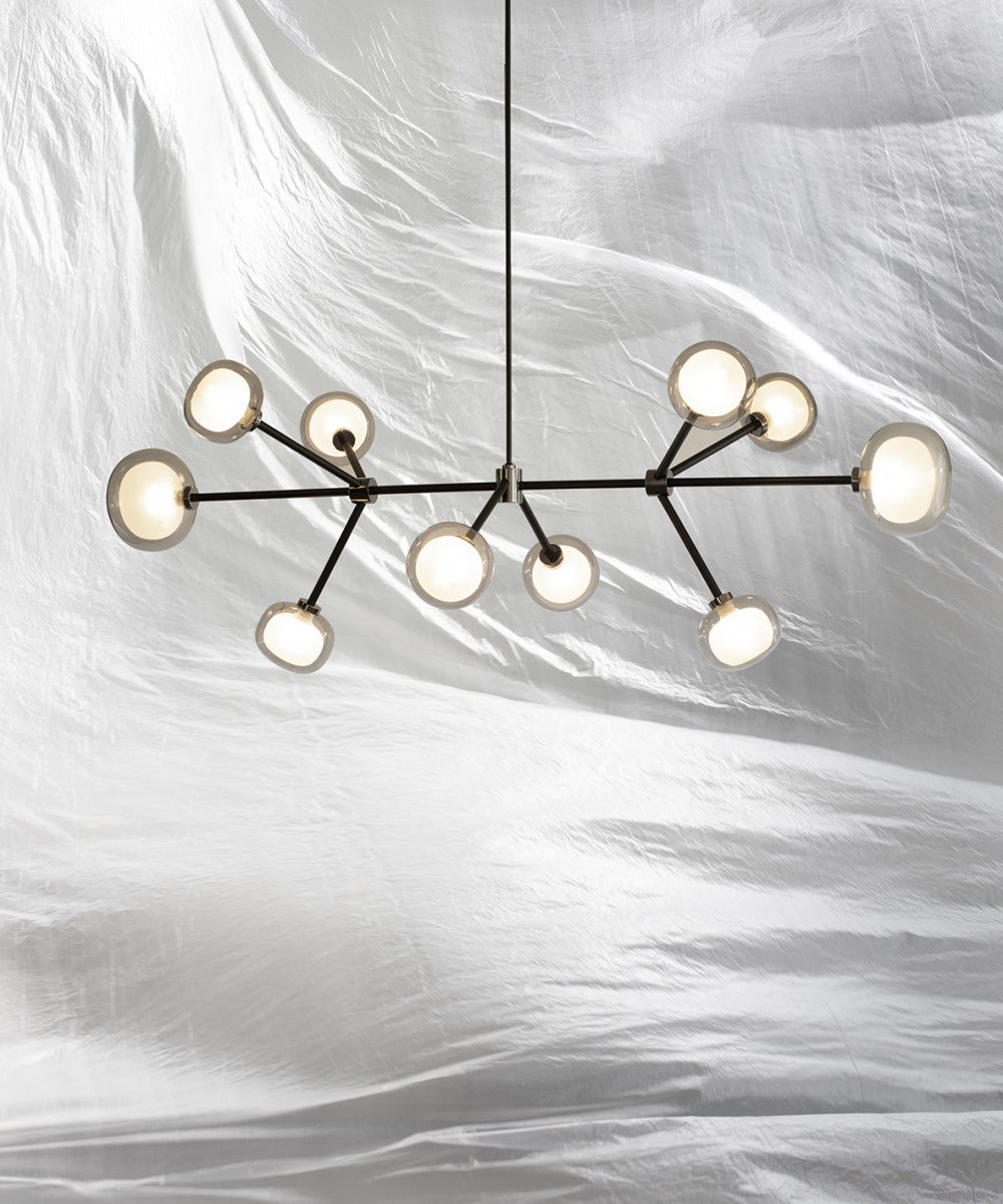 Clérachic chandelier with clear-rimmed glass globes on black arms, hung against rumpled white fabric from a thin black rod.