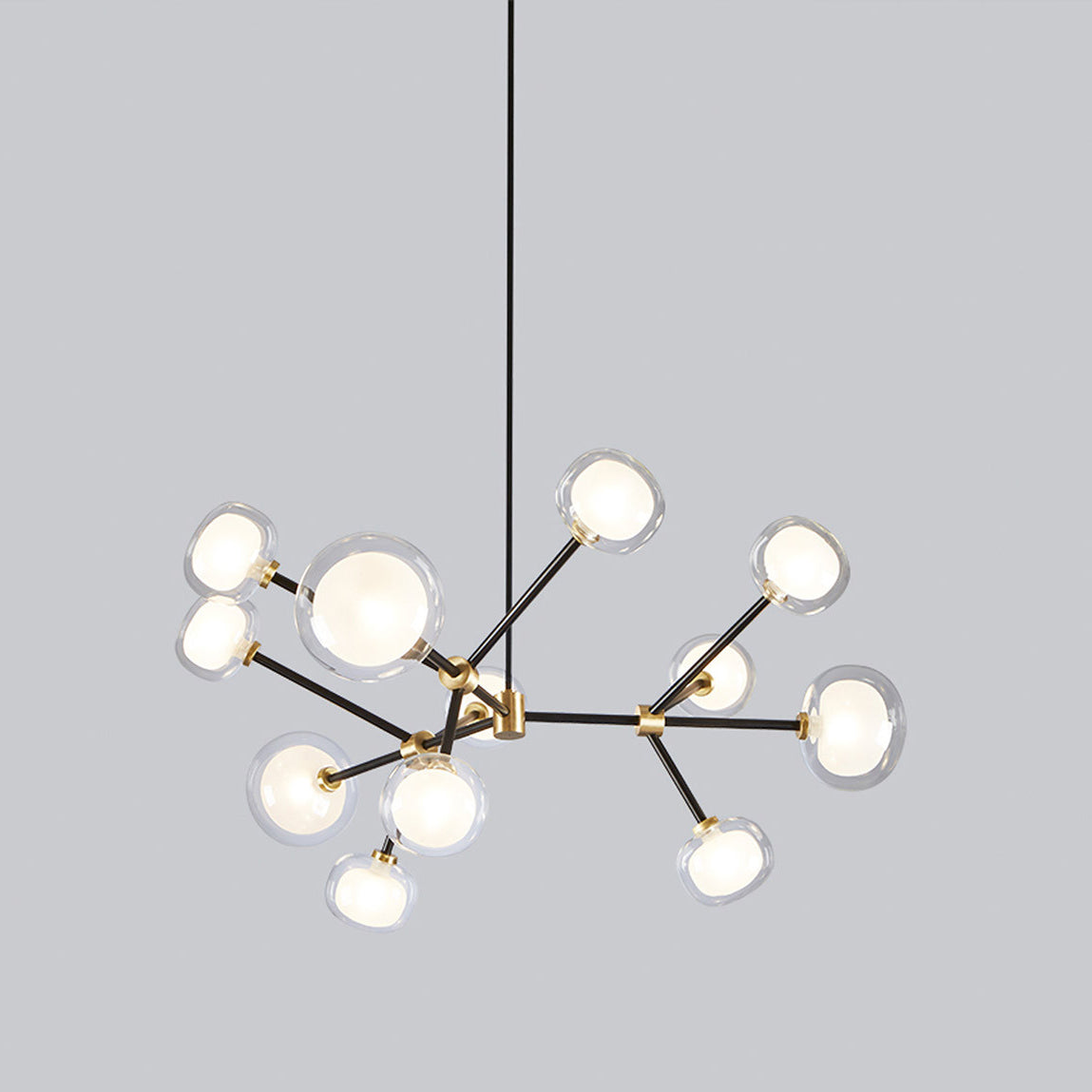 Clérachic chandelier on a grey backdrop, turned at an angle so its black arms and glass globes spread unevenly around the brass centre.