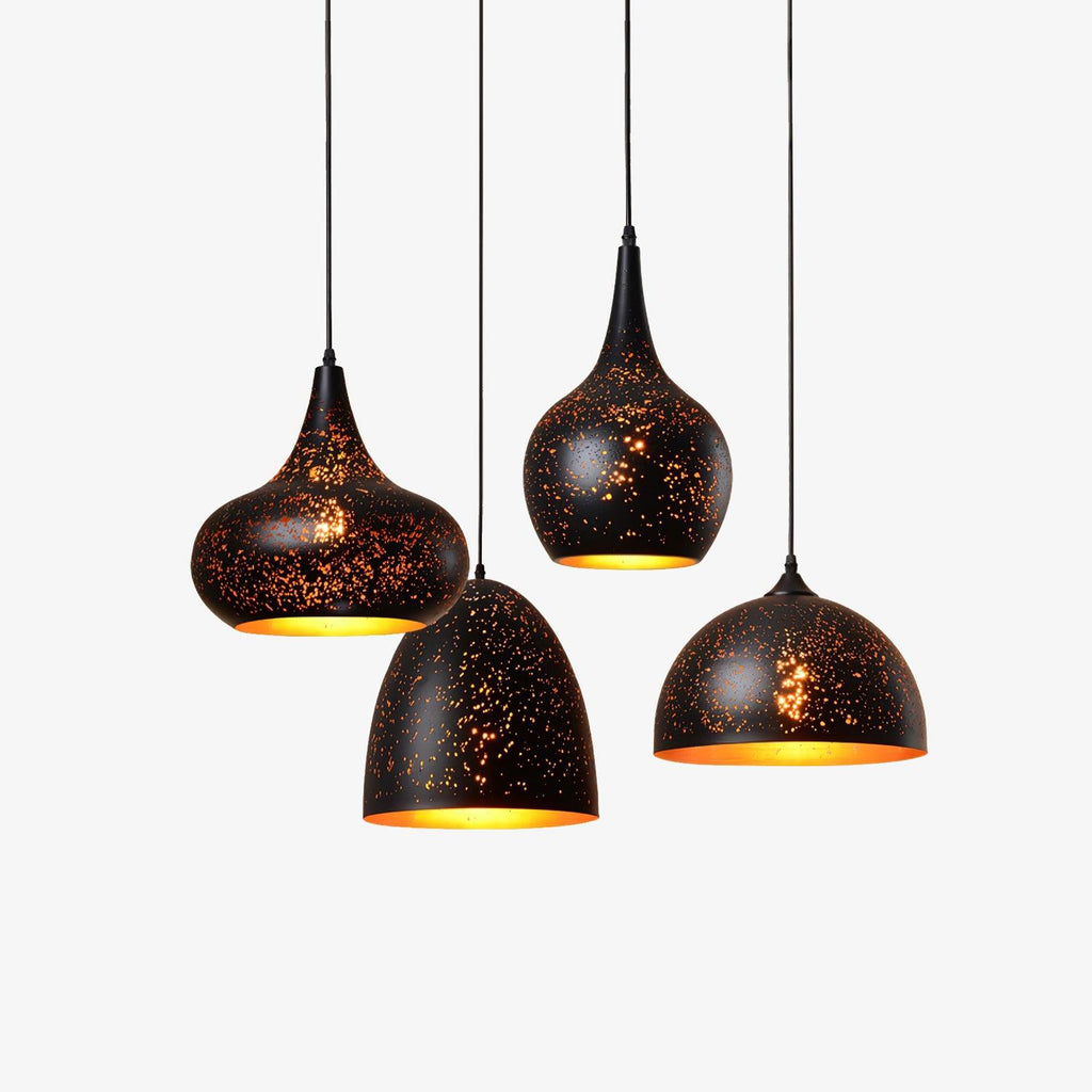 Four Clérachic pendant lights in different shapes hung at staggered heights, each a black perforated shade with a gold interior, on a white backdrop.