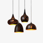 Four Clérachic pendant lights in different shapes hung at staggered heights, each a black perforated shade with a gold interior, on a white backdrop.