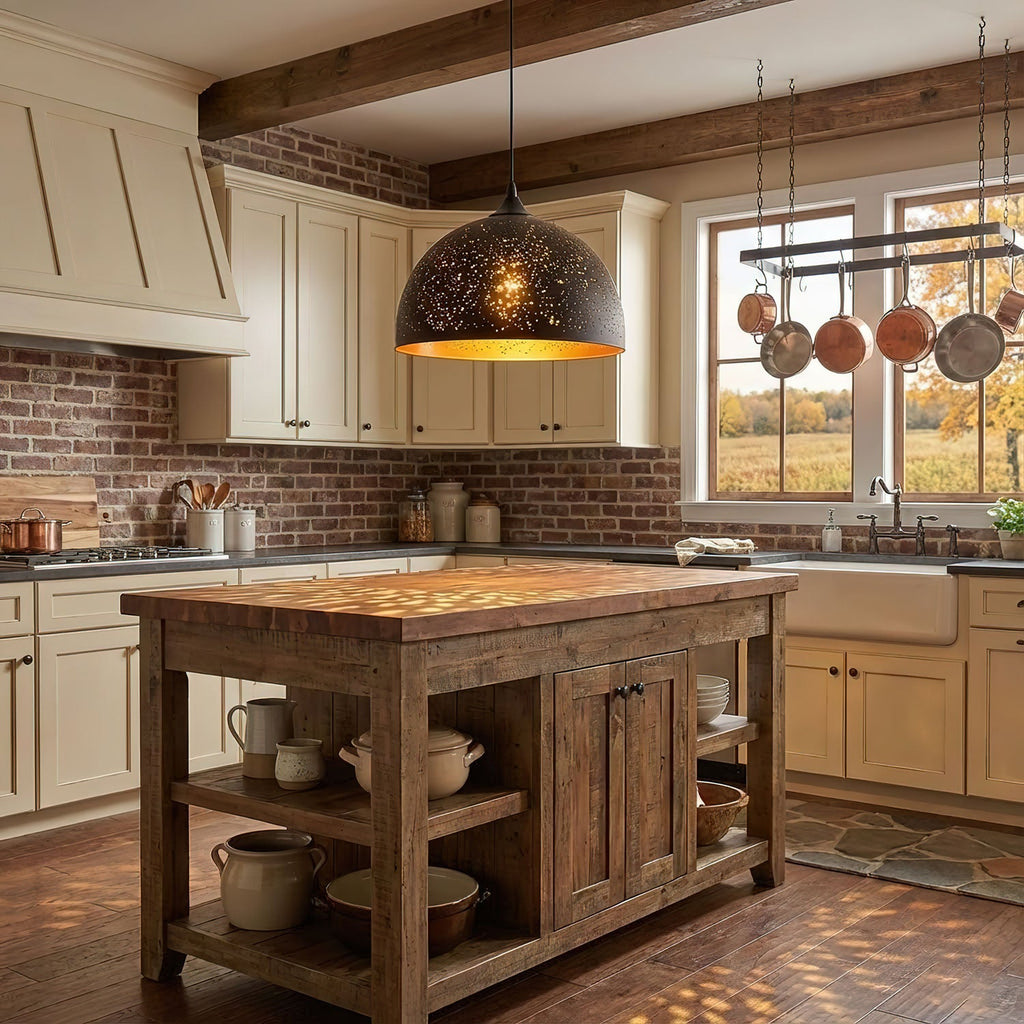 Domed Clérachic pendant with a perforated black shade hanging over a rustic timber kitchen island, with copper pans and a brick wall behind.