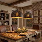 Two wide Clérachic dome pendants above a farmhouse dining table, scattering small spots of light over place settings and a foliage centrepiece.