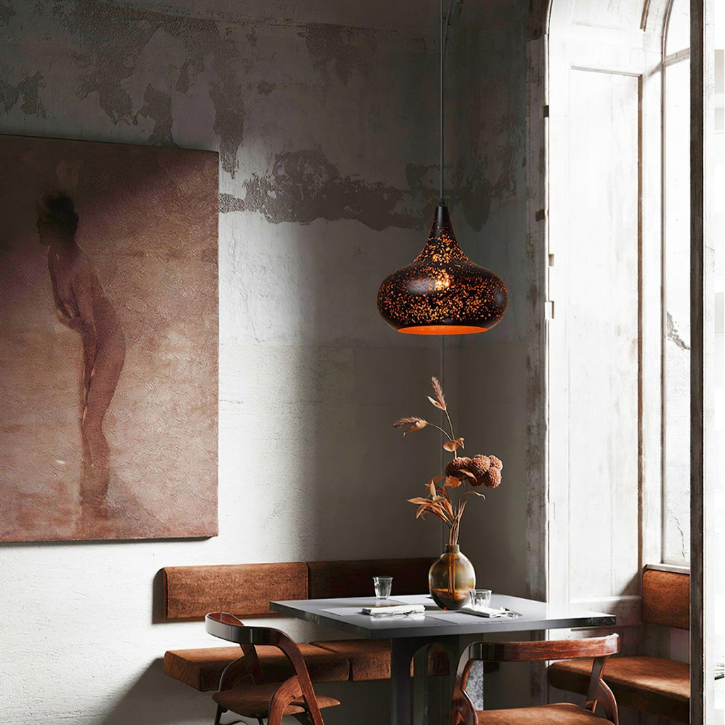 Teardrop Clérachic pendant above a small square table in a corner with a weathered plaster wall, a large framed painting and a vase of dried stems.