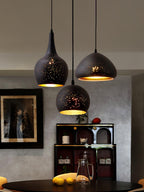 Three Clérachic pendants, a teardrop, a round dome and a wide dome, at staggered heights above a dark table with lemons, in a grey room.