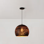 Round Clérachic pendant with a black perforated shade, hanging from a ceiling plate on a thin black cord against a white wall.