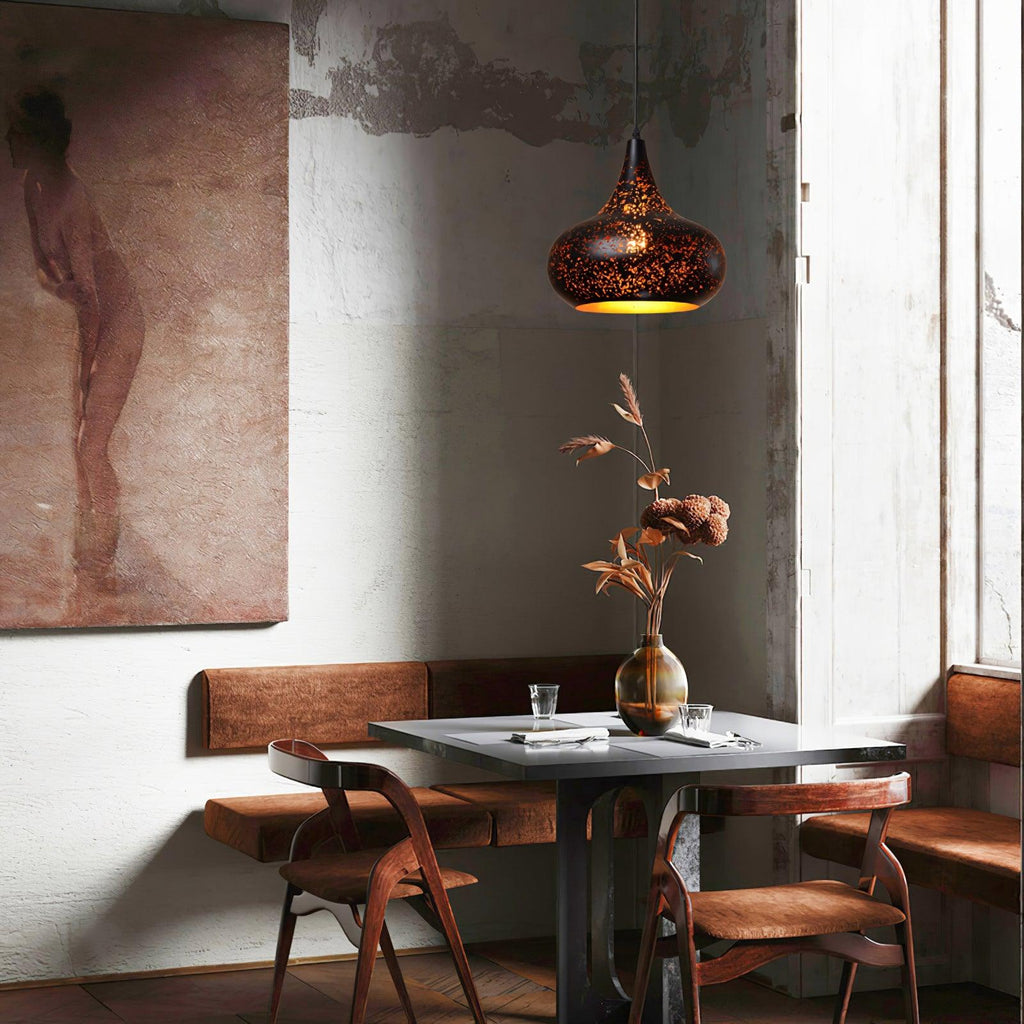 Clérachic teardrop pendant hanging in a high-ceilinged room above a table with a tall vase of dried leaves, beside a large muted painting.