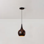 Teardrop Clérachic pendant with a black perforated shade and a gold interior, hanging from a round ceiling plate against a white wall.