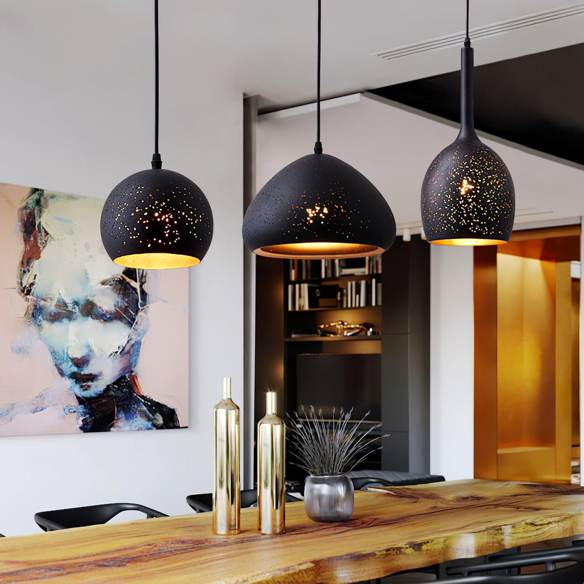 Three Clérachic pendants over a polished wood counter, with a painted portrait and gold bottles in a modern dining space behind them.