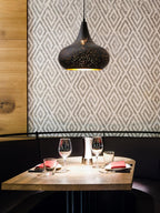 Clérachic teardrop pendant above a restaurant booth with a set table, against a wall of geometric grey and white wallpaper.