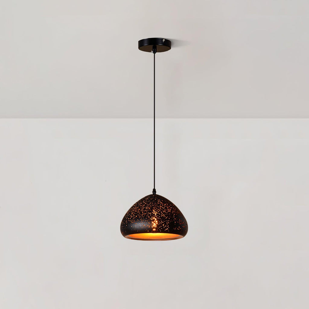 Low, wide Clérachic pendant with a rounded black shade dotted with small perforations, hanging from a ceiling plate on a white wall.