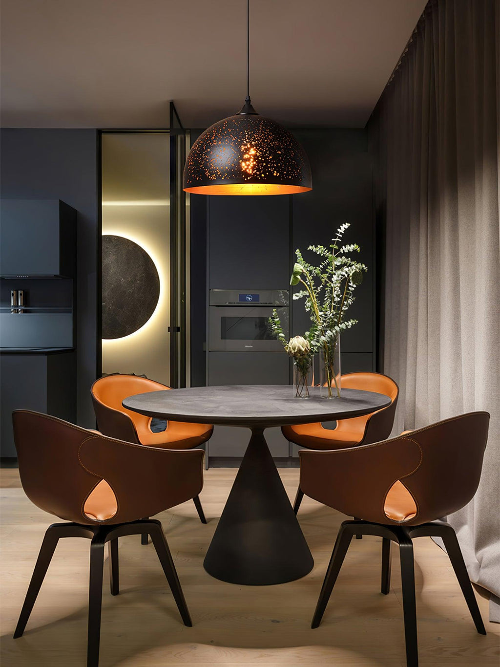 Clérachic domed pendant above a round dark dining table with four tan chairs, in a moody room with a glowing wall circle.