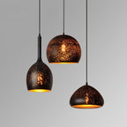 Three Clérachic pendants of different shapes and drops against a pale grey backdrop, each with a perforated black shade and gold lining.