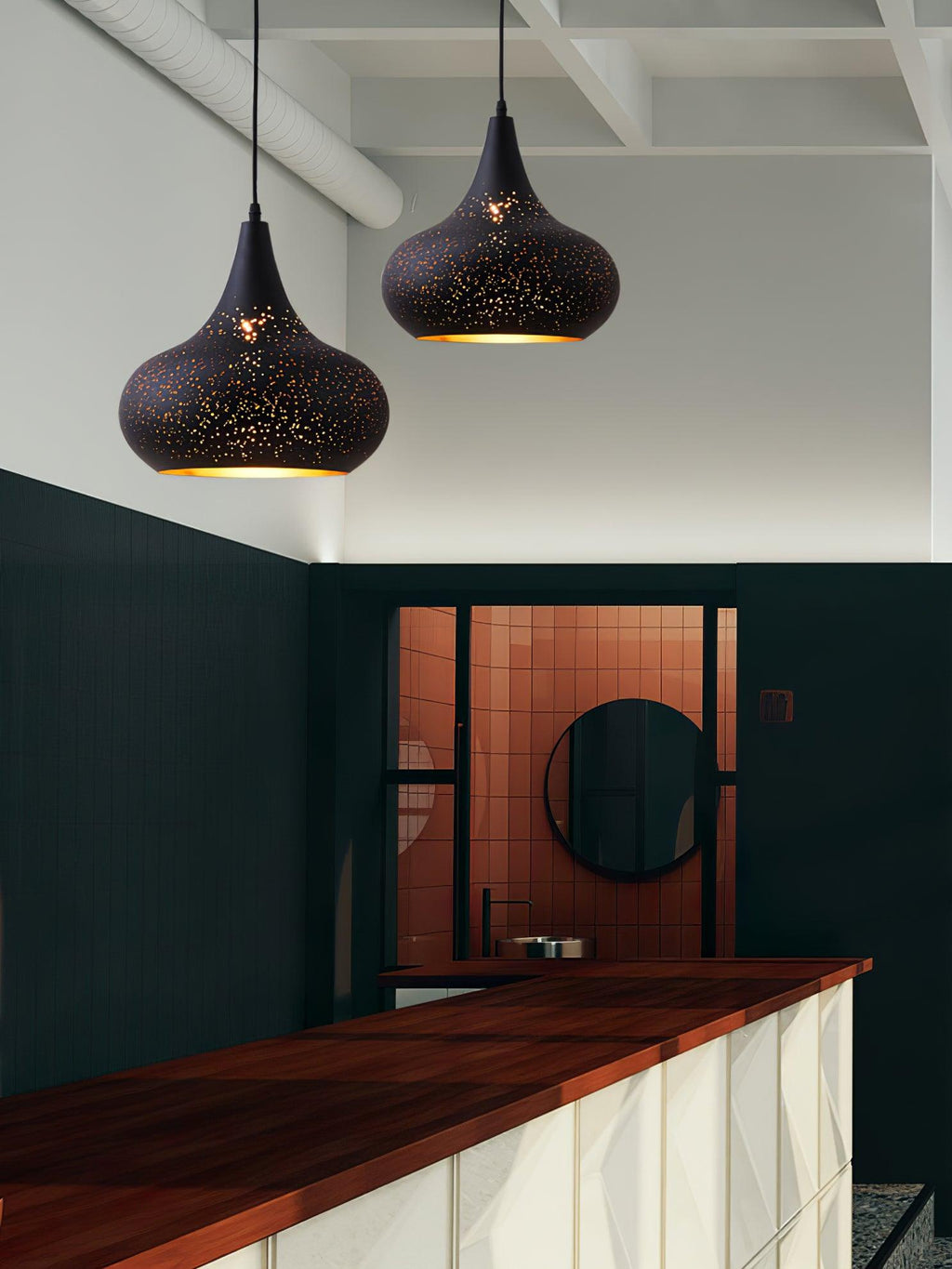 Pair of teardrop Clérachic pendants in a tall white room with exposed beams, a dark green wall and a copper-tiled alcove below.