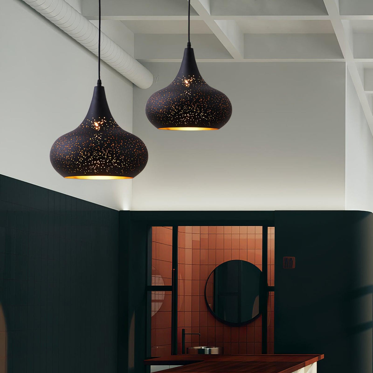 Closer view of two teardrop Clérachic pendants against a white ceiling, with a dark green wall and a copper-tiled alcove with a round mirror.