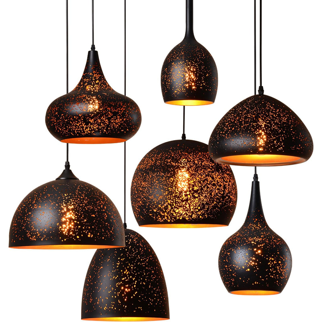 Seven Clérachic pendants close together at varied heights, their speckled black shades glowing with warm gold light from within.