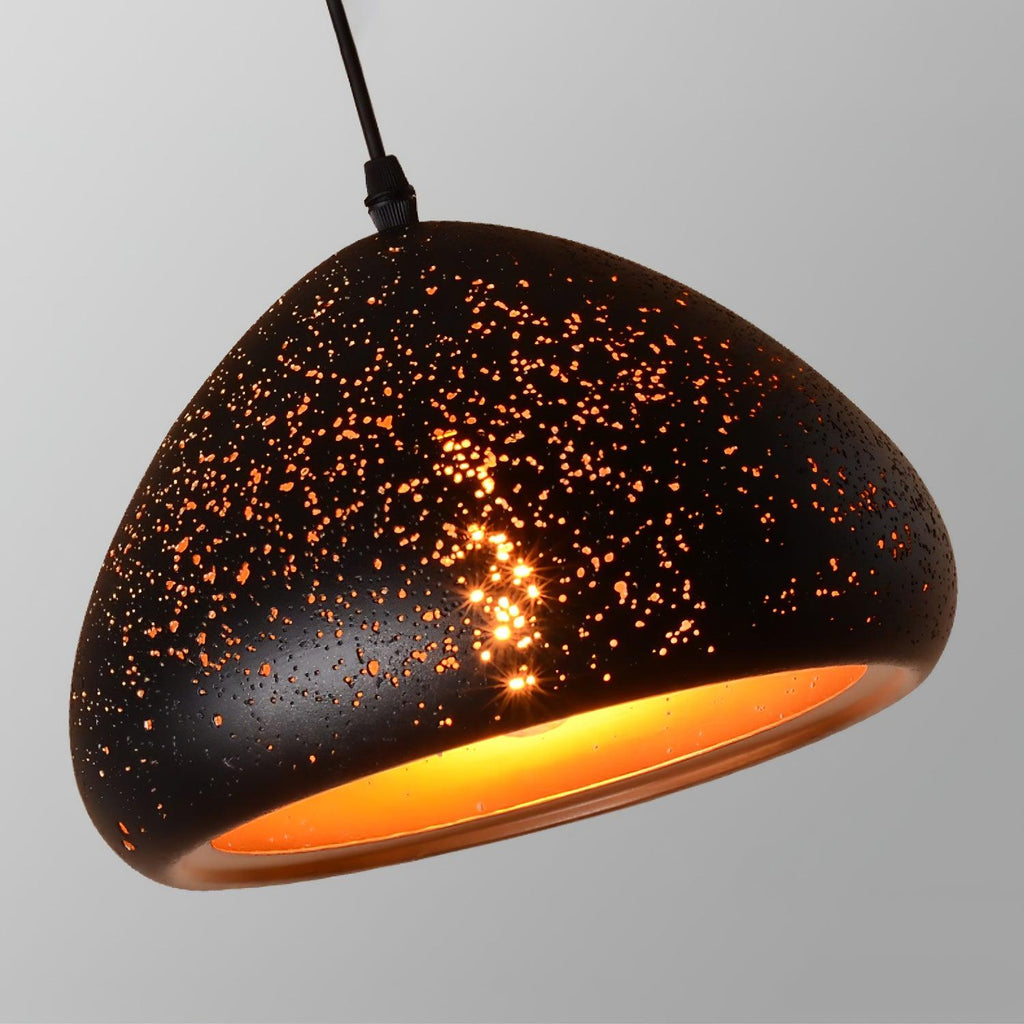 Close view of an oval Clérachic pendant shade tilted to show its dense perforations and the gold lining glowing inside.