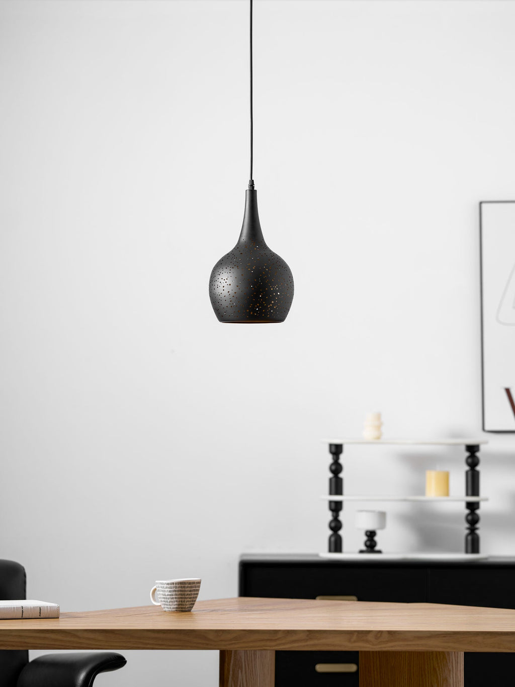 Teardrop Clérachic pendant hanging in a bright room, with a wooden table and a cup below and a framed print on the white wall.