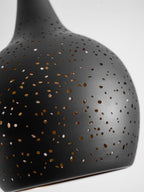 Detail of the matt black shade of this Clérachic pendant, showing its scattered small perforations and the curve of the rim.