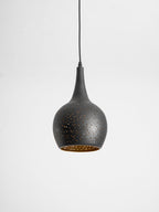 Teardrop Clérachic pendant tilted slightly toward the camera, showing the gold lining inside its perforated black shade.