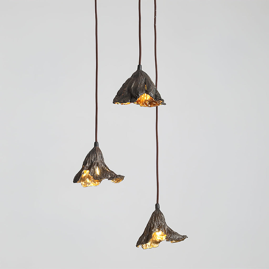 Three Clérachic pendants with black outer shades and gold interiors hang at different drops against a light grey backdrop.