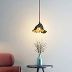 A Clérachic pendant glows over a small side table with a teal glass vase of bare twigs, beside a red-pink armchair.