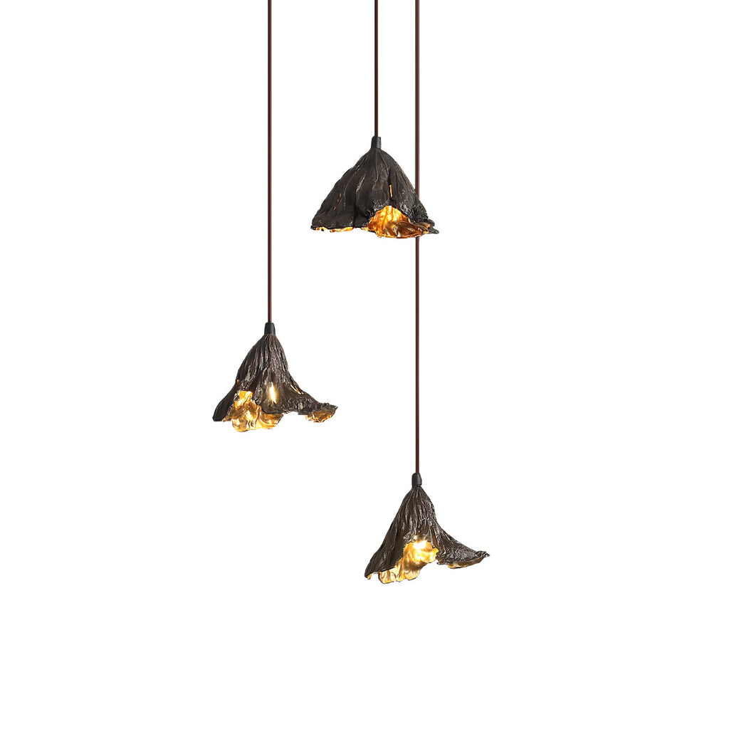 Three Clérachic pendants hang at staggered heights on a white backdrop, shades black outside and gold within.