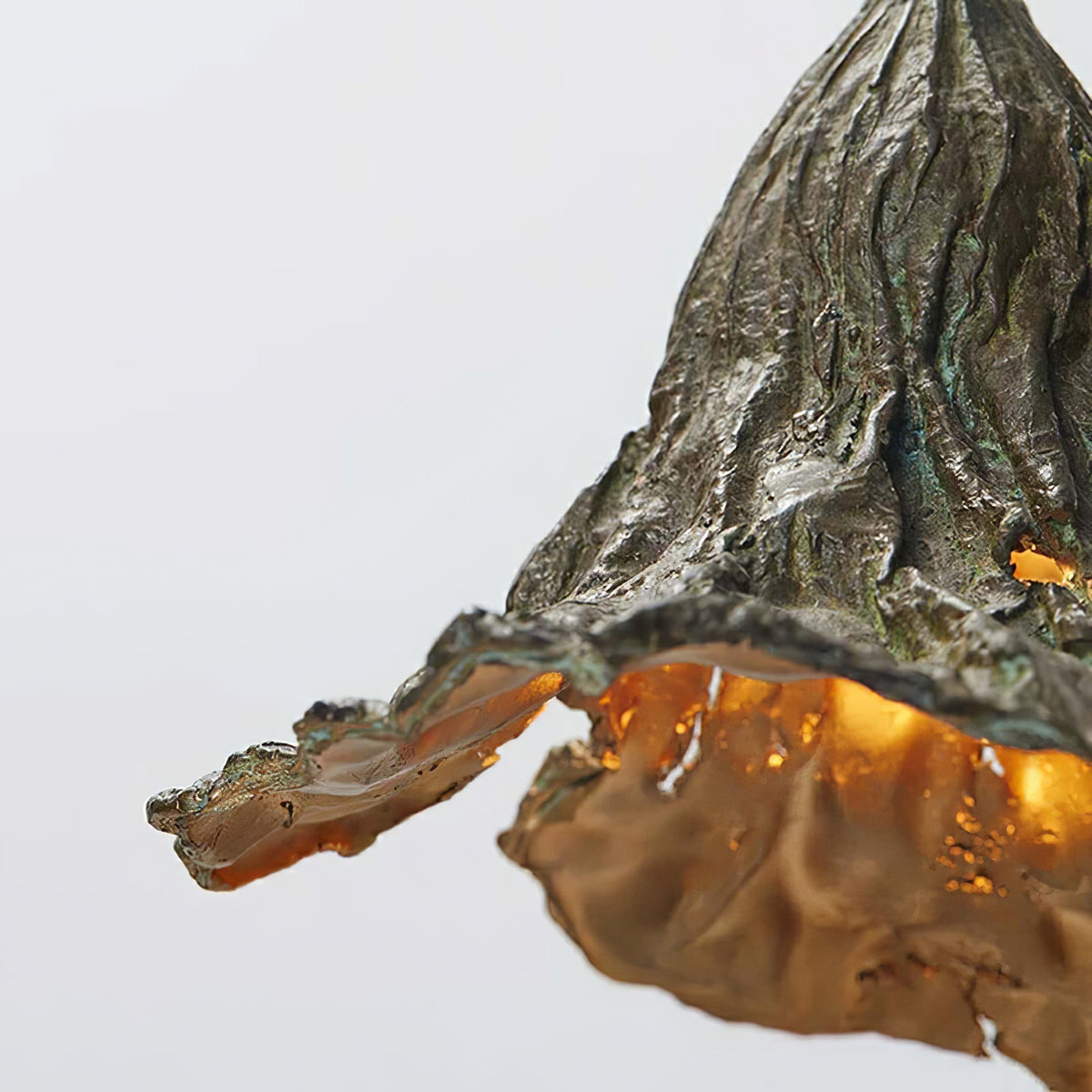 Close view of the rough greenish-bronze outer texture of this Clérachic pendant, with its gold inside showing at the rim.