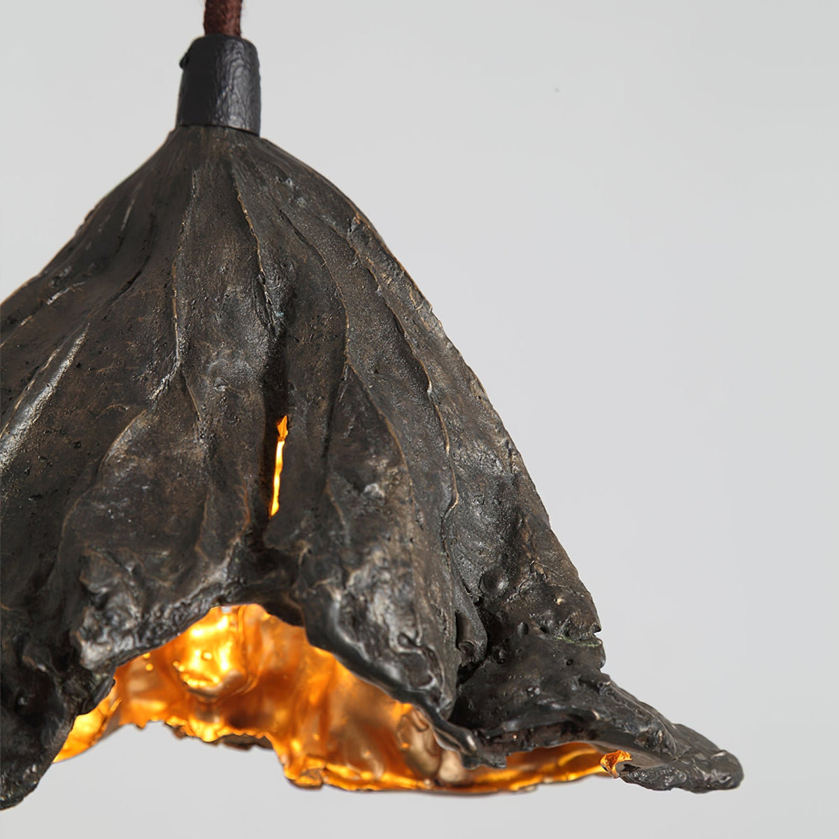 Close view of the veined black outer surface on this Clérachic pendant, with a gold interior glowing below.