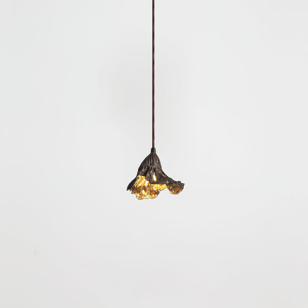 A small Clérachic pendant with a dark ruffled shade and gold interior hangs from a thin cord against a pale backdrop.