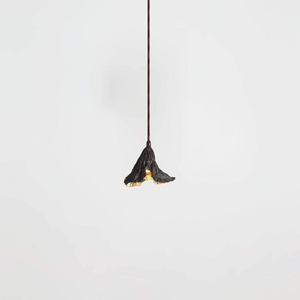 A small Clérachic pendant with a dark crinkled shade hangs from a thin cord, seen on a pale backdrop.