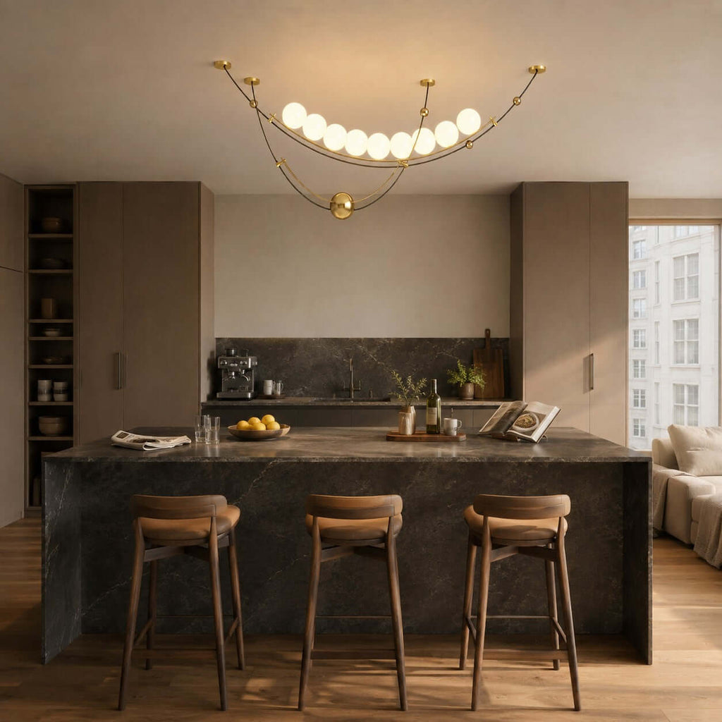 This Clérachic pendant hangs over a dark stone kitchen island with three wooden stools, in a room of taupe cabinetry.