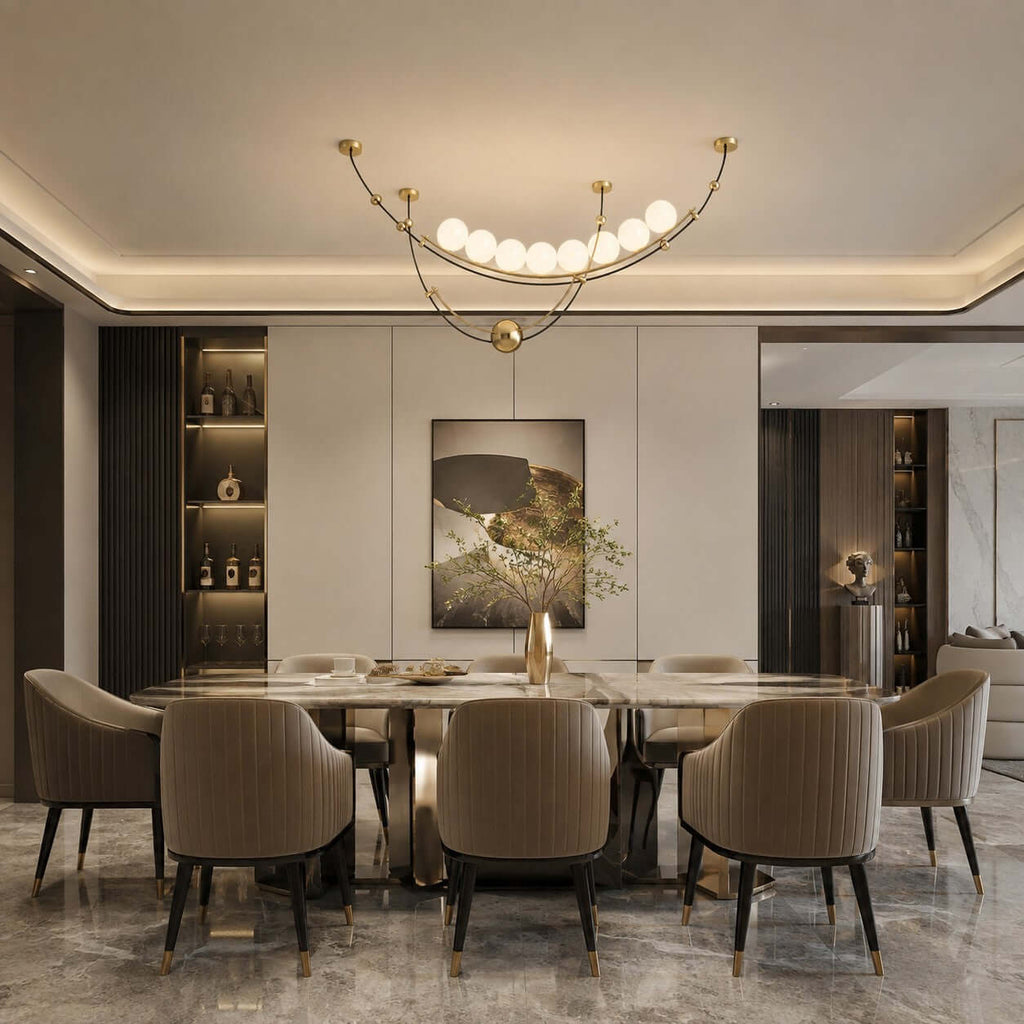 A Clérachic pendant with a line of lit globes over a long dining table, in a room with a cove-lit ceiling and striped chairs.