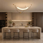 This Clérachic pendant over a marble island with four round-backed stools, with dark wood tall units on either side.