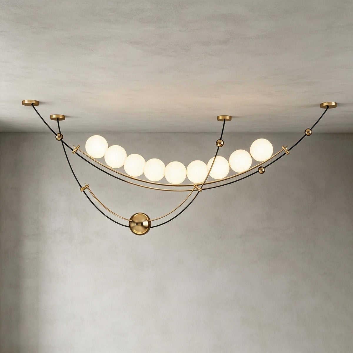 Underside view of this Clérachic pendant against a grey plaster wall, with its row of round white globes and brass ceiling plates.