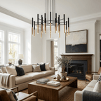 A Clérachic tubular chandelier hangs in a bright living room with a cream sofa, a wooden coffee table and a fireplace.