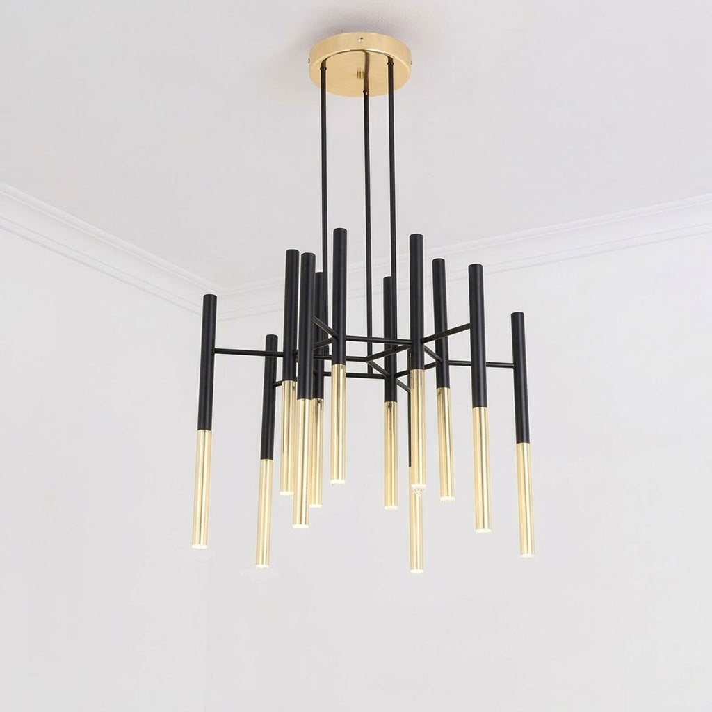 A Clérachic chandelier with black arms and gold-finish tubes hangs from the ceiling of a plain white room, seen from below.
