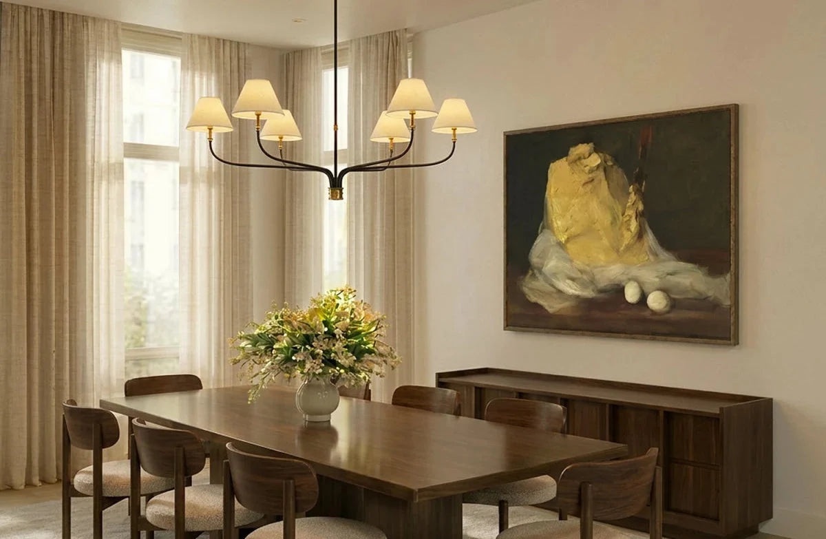 Clérachic six-arm chandelier hanging above a walnut dining table, with sheer curtains and a large still-life painting.