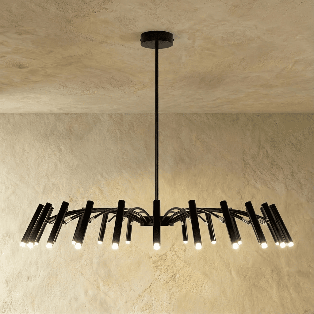 Every head glows warm on this extended black iron chandelier, arched arms spanning wide above a plain studio backdrop, Clérachic hero shot.