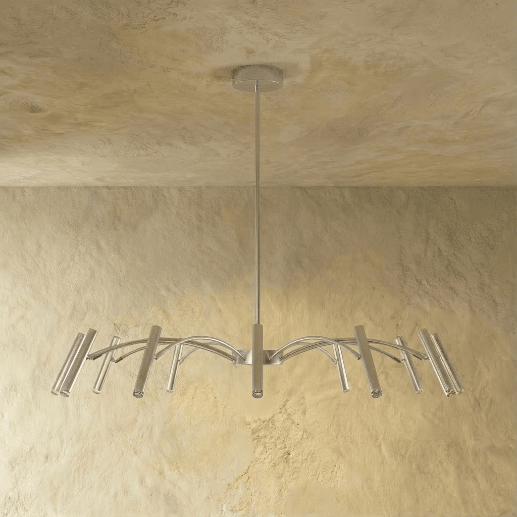 The silver-toned chandelier's compact arm spread and tube heads are shown straight-on against a plaster wall in this Clérachic hero shot.