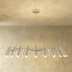 A fuller silver-toned chandelier spreads arched arms and many cylindrical heads, each catching warm light in this Clérachic hero shot.